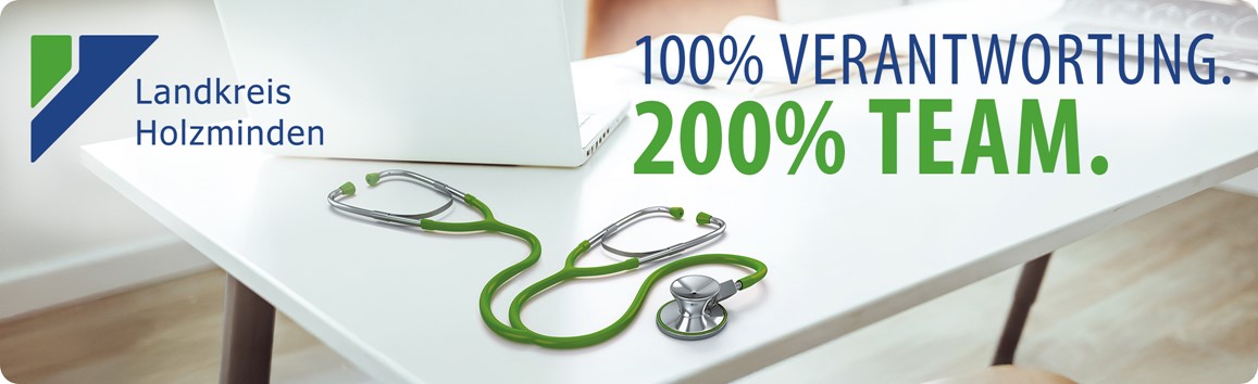 Es ist ein Tisch zu sehen, wo ein Laptop und ein Stethoskop drauf liegt. Dort neben steht 100 % Verantwortung und 200 % Team.