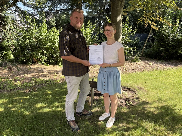 Die Fördermittelberater Thomas Greger und Tessa Harries halten Ihren Flyer der Klimafördermittelberatung für Kommunen im Landkreis Holzminden in die Kamera&nbsp;&copy;&nbsp;Landkreis Holzminden
