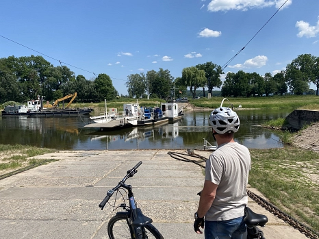 Eine Person mit Fahrrad vor einem Fluss, auf dem eine Fähre übersetzt.&nbsp;&copy;&nbsp;Landkreis Holzminden / Waltraud Grueger